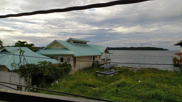 A house with a green roof near a body of water.