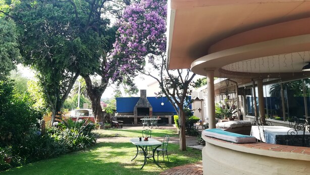 A patio area with a brick pathway, a round table with chairs, and a barbecue grill. - 3@Marion Guesthouse (Pretoria)