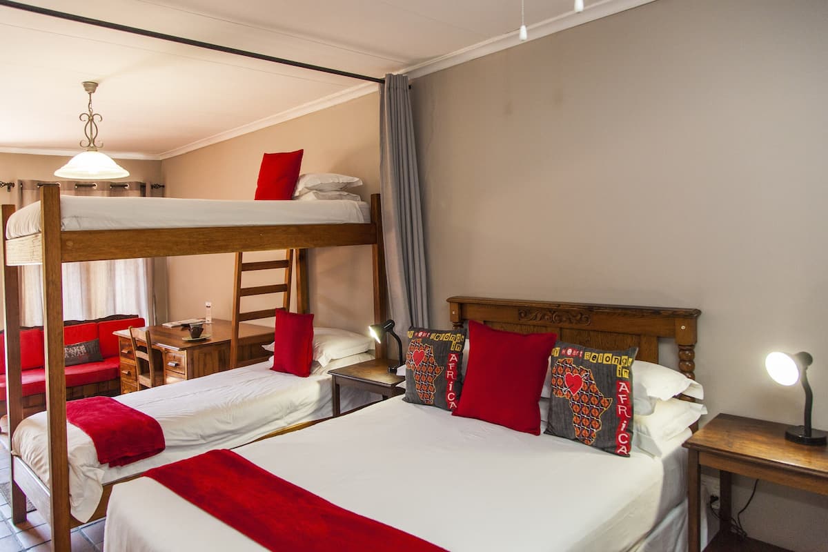 Een hotelkamer met twee bedden, een stapelbed, een bureau en een stoel.