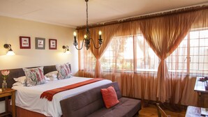 A bedroom with a bed, a sofa, a table, and a chandelier. - 3@Marion Guesthouse (Pretoria)