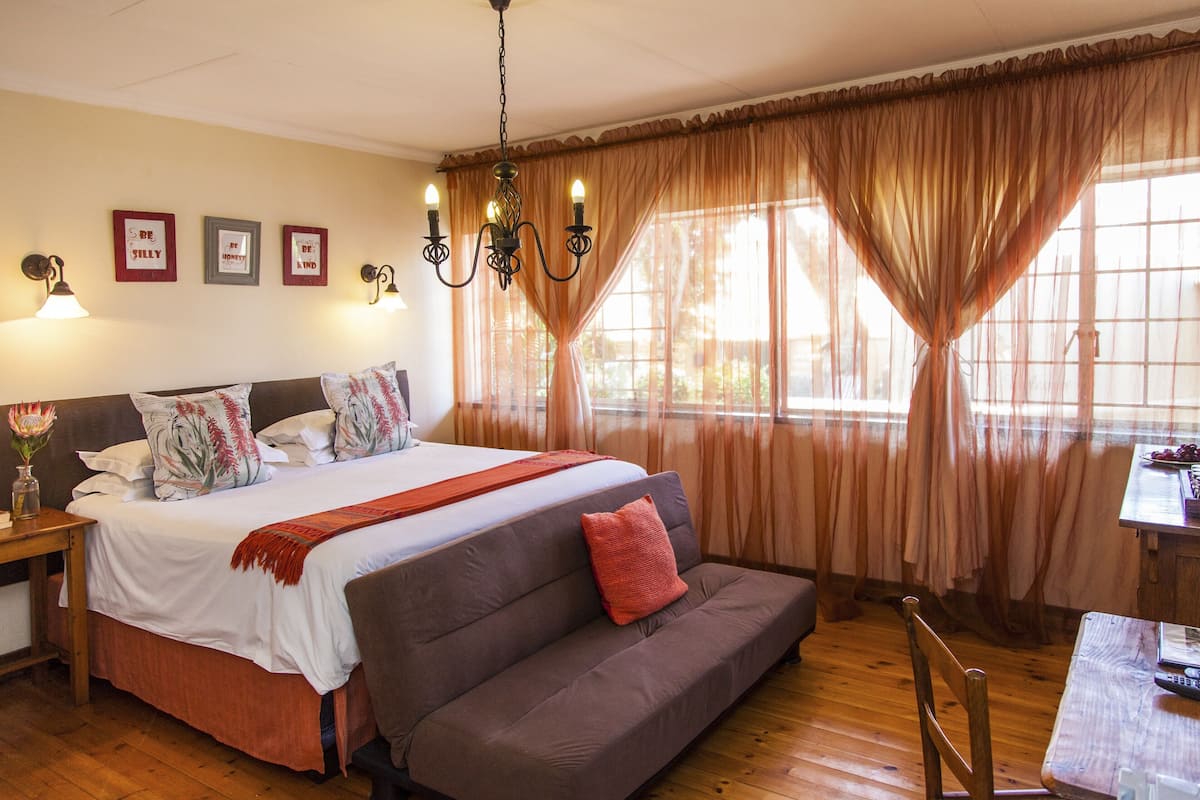 Een slaapkamer met een bed, een bank, een tafel en een kroonluchter.