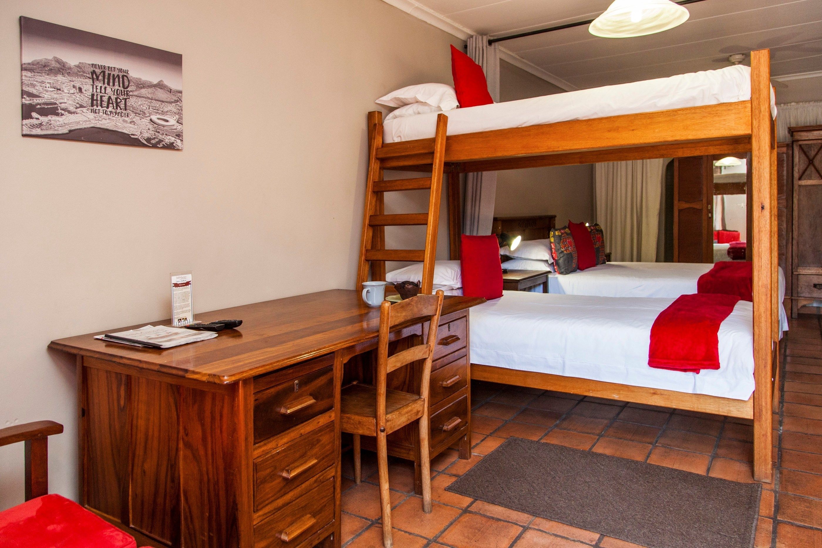 A bunk bed room with a desk, chair, and a mirror.