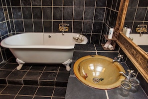 Une salle de bain avec une baignoire sur pieds, un lavabo en céramique et un miroir.