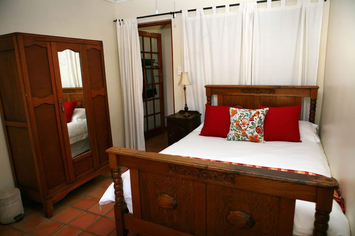 Een slaapkamer met een houten bed, een kledingkast en een spiegel.