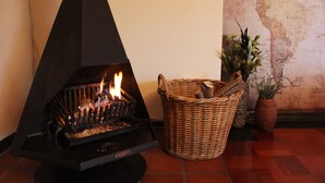 A wood-burning stove with visible flames, a wicker basket, and a map on the wall. - 3@Marion Guesthouse (Pretoria)