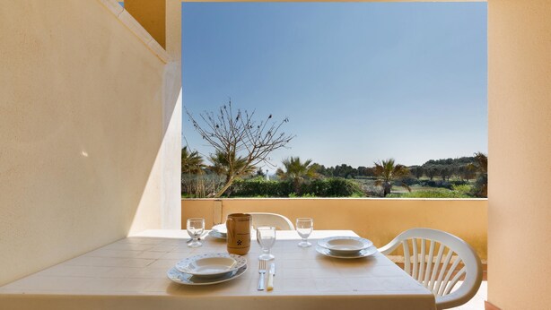 A balcony table set with plates, glasses, and cutlery, overlooking a scenic landscape with trees and hills. - Casa Frulli (Uggiano la Chiesa)