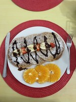 A plate with pancakes, strawberries, bananas, and orange slices on a red placemat.