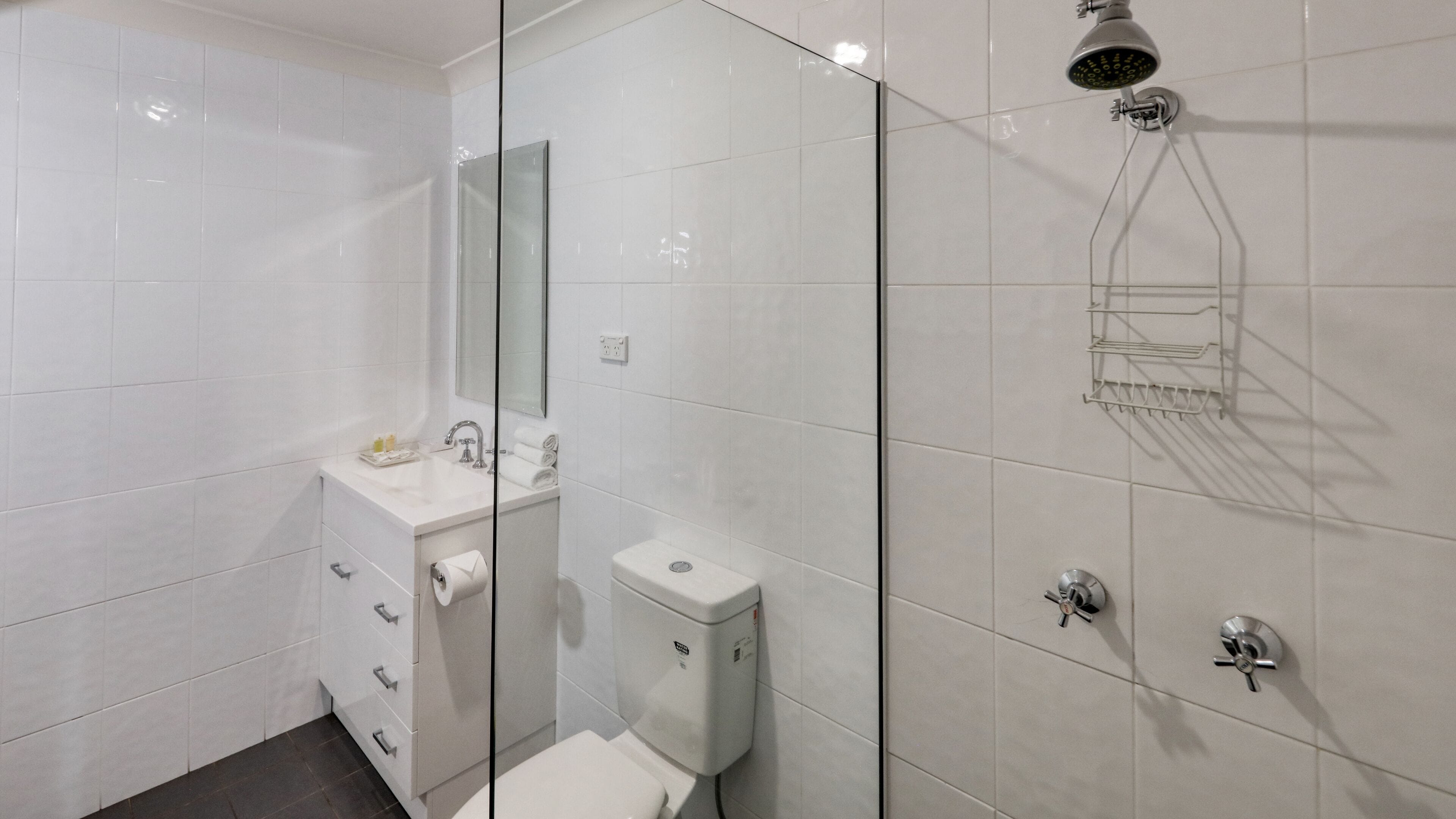 A modern bathroom with a glass shower enclosure, a white sink with a mirror, and a toilet.
