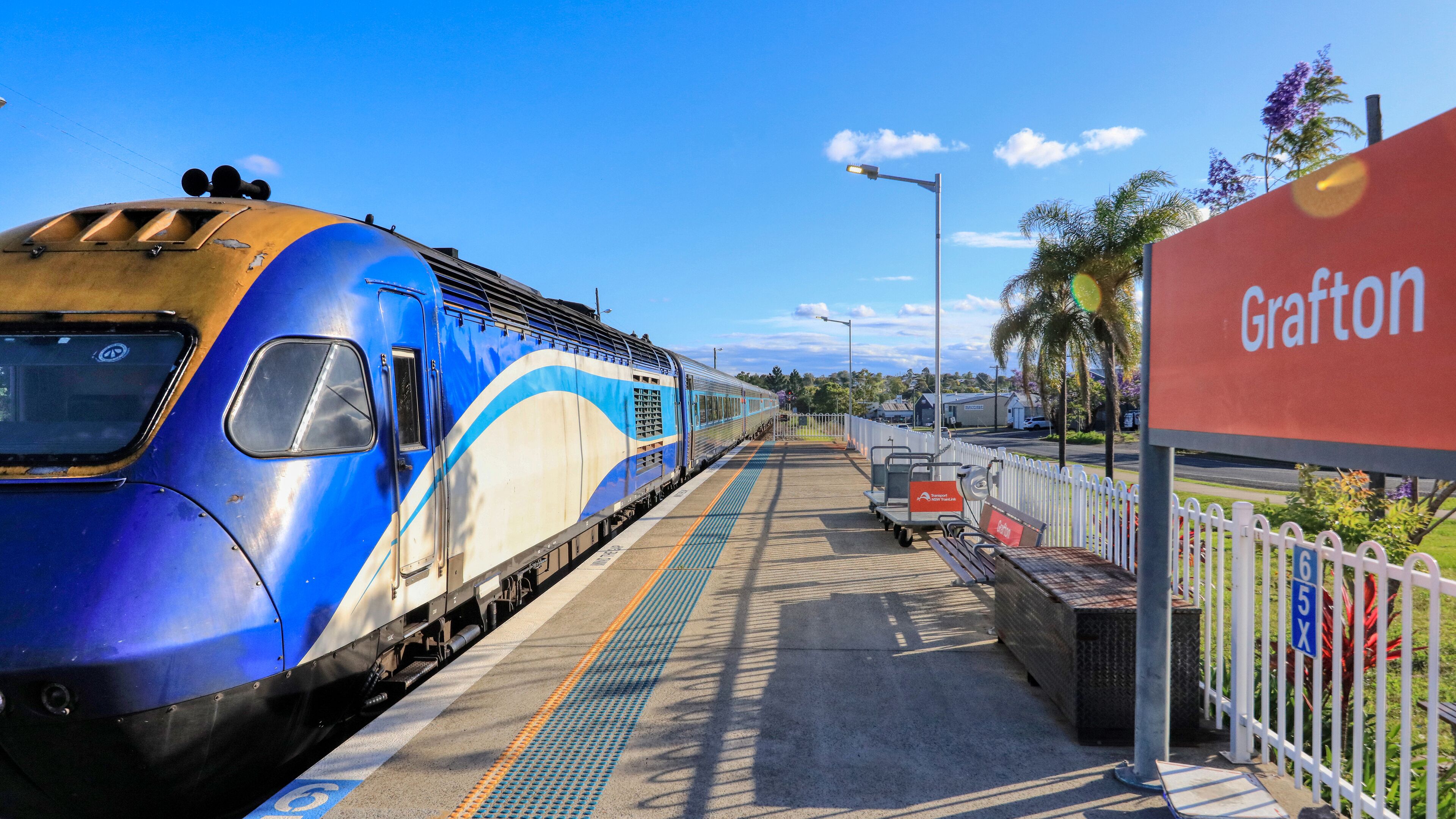 A train at a station platform with a sign reading "Grafton".