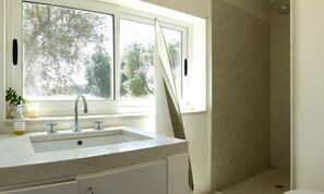 Une salle de bain équipée d’un lavabo, de deux robinets, d’une fenêtre et d’un espace douche.
