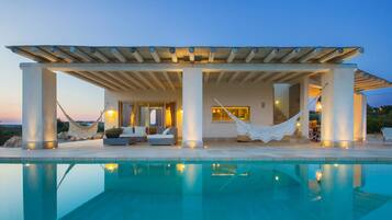 Relax by the rectangular pool surrounded by a patio with a pergola and comfortable seating.