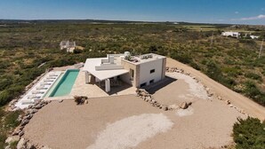 A modern villa with a pool, surrounded by a dry landscape.
