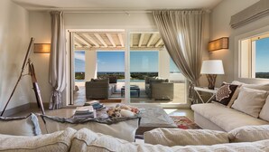 A spacious living room with a large sofa, a coffee table, and a view of the outdoor patio area.