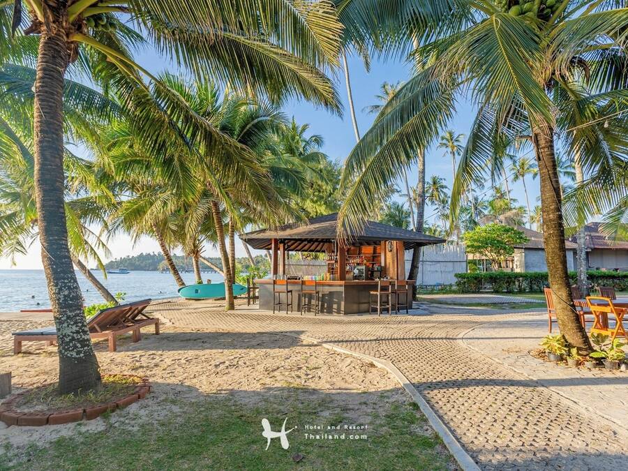 A beachside bar area with a wooden structure, seating, and a view of the sea.