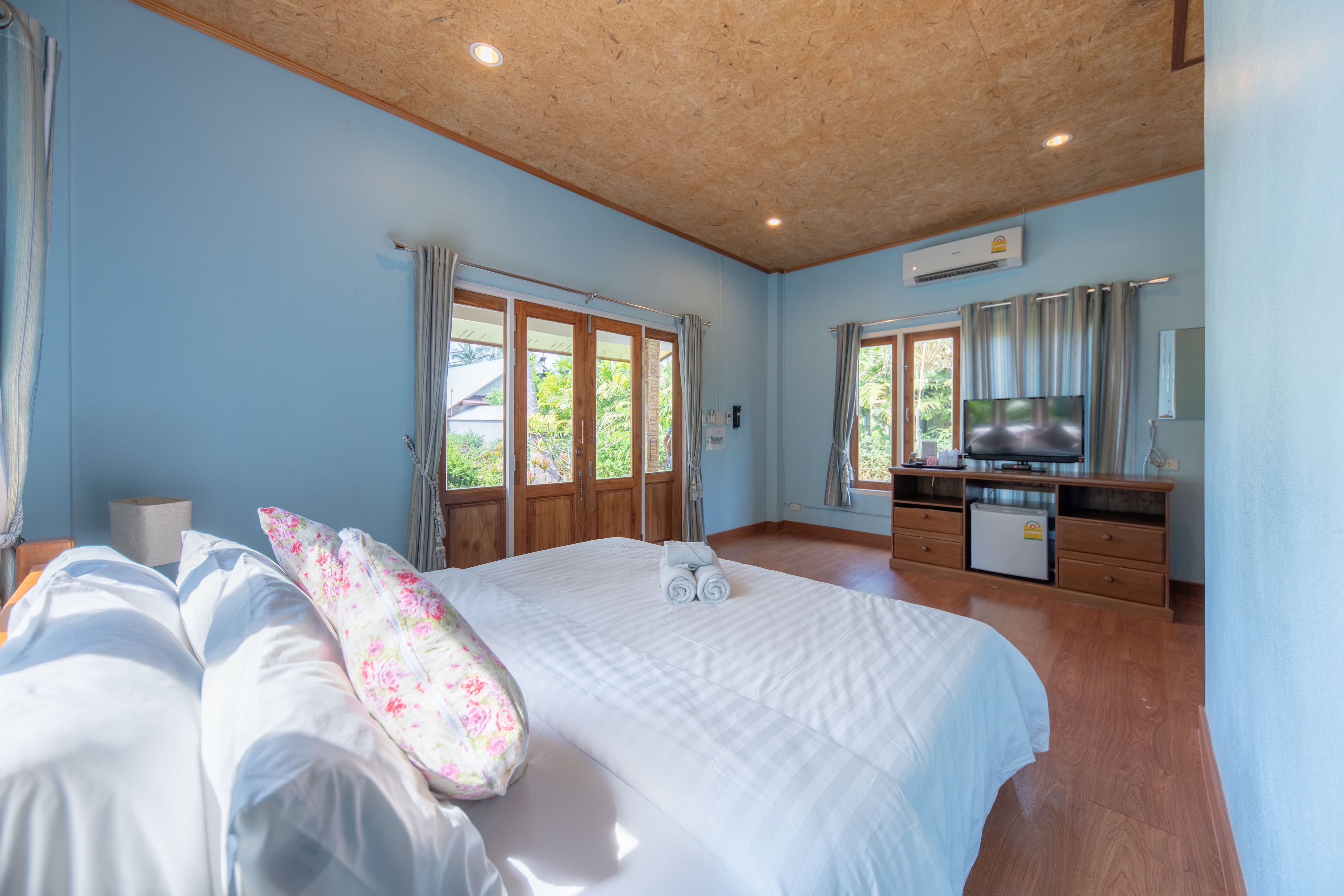 Un dormitorio con una cama grande, techo de madera y un aparador con televisor.