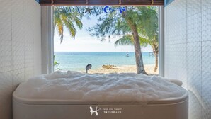 Una bañera con vista a una playa y palmeras.