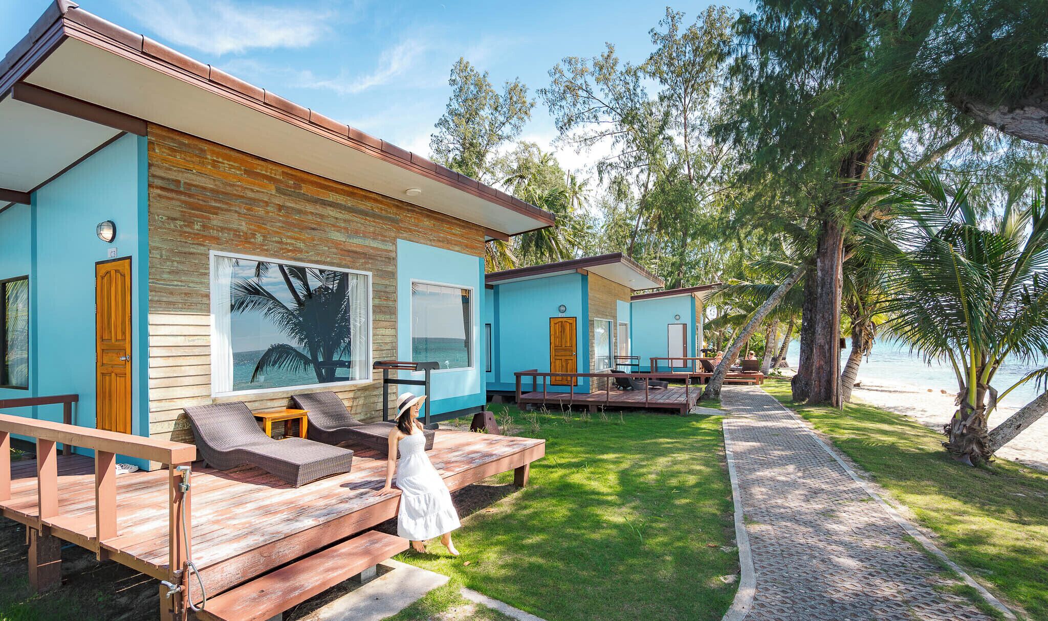 A beachfront property with two guest rooms, each featuring a wooden deck and a large window.