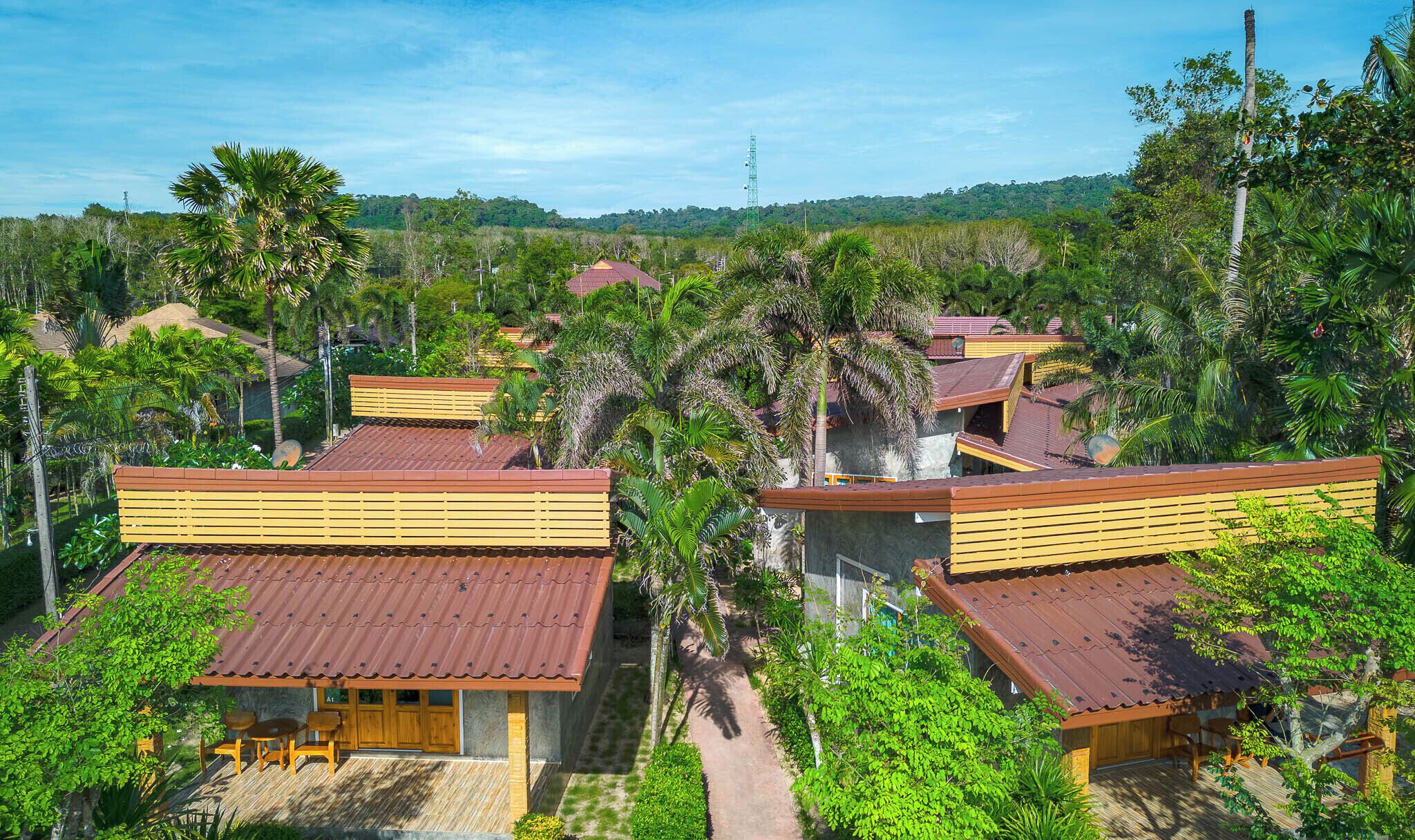 Un complexe hôtelier composé de plusieurs bâtiments de style bungalow, chacun doté d’un toit recouvert de tuiles rouges et de balcons en bois.
