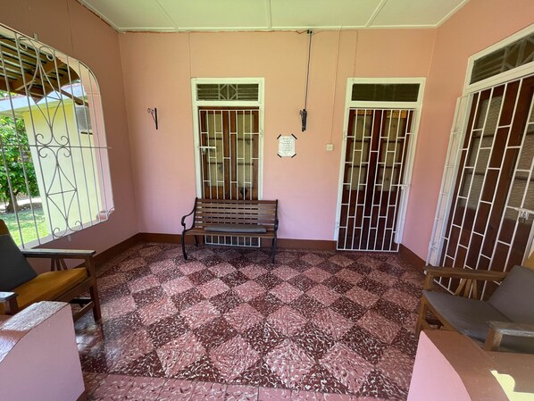 A room with a patterned floor, a bench, and barred windows. - Little Shaw Park Guest House (Ocho Rios)