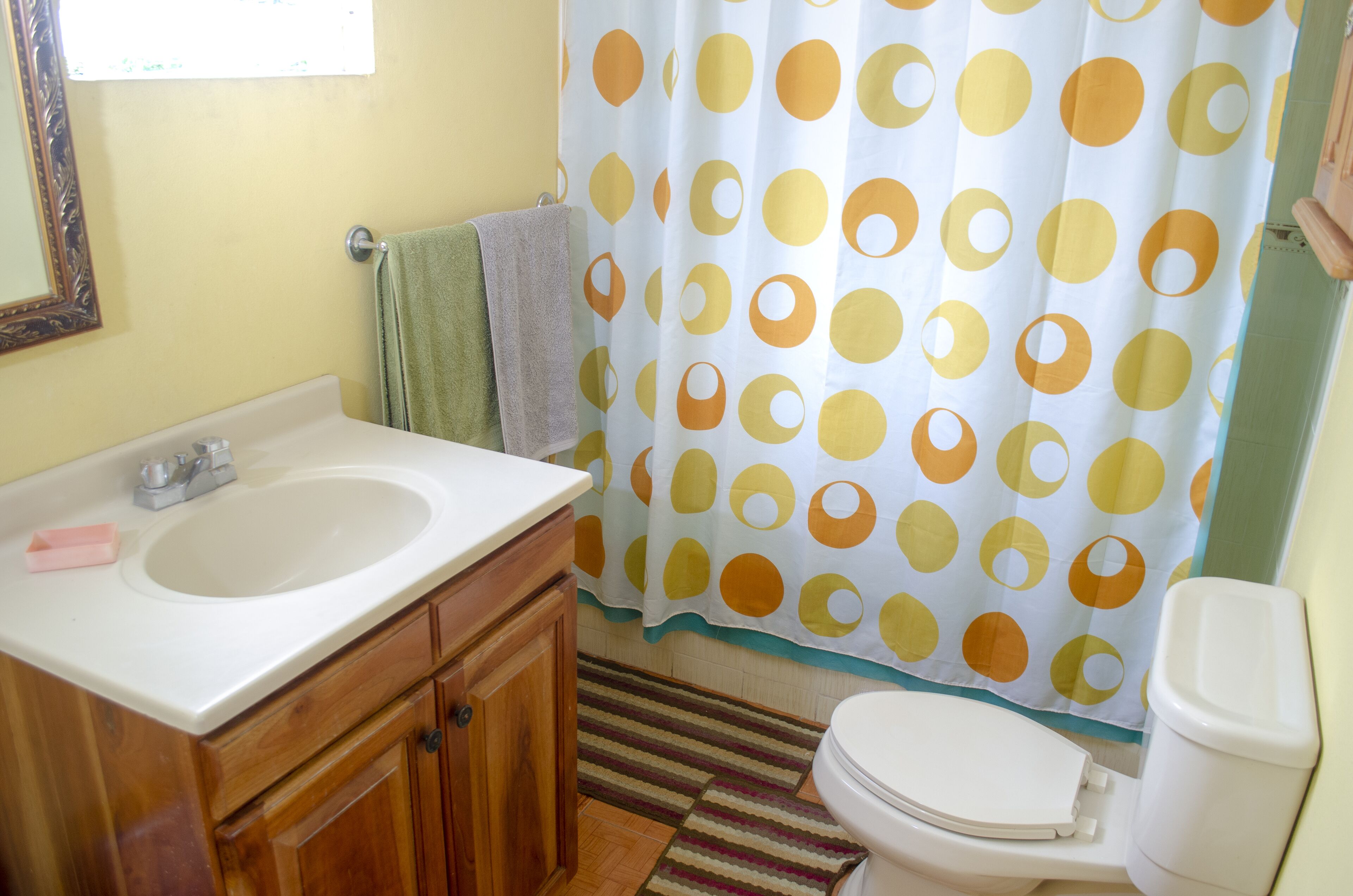 A bathroom with a sink, mirror, toilet, and shower curtain.