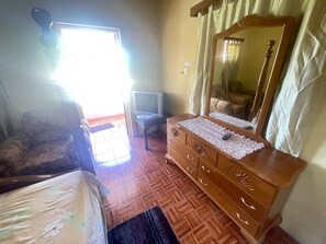 A bedroom with a wooden dresser, a television, and a bed.