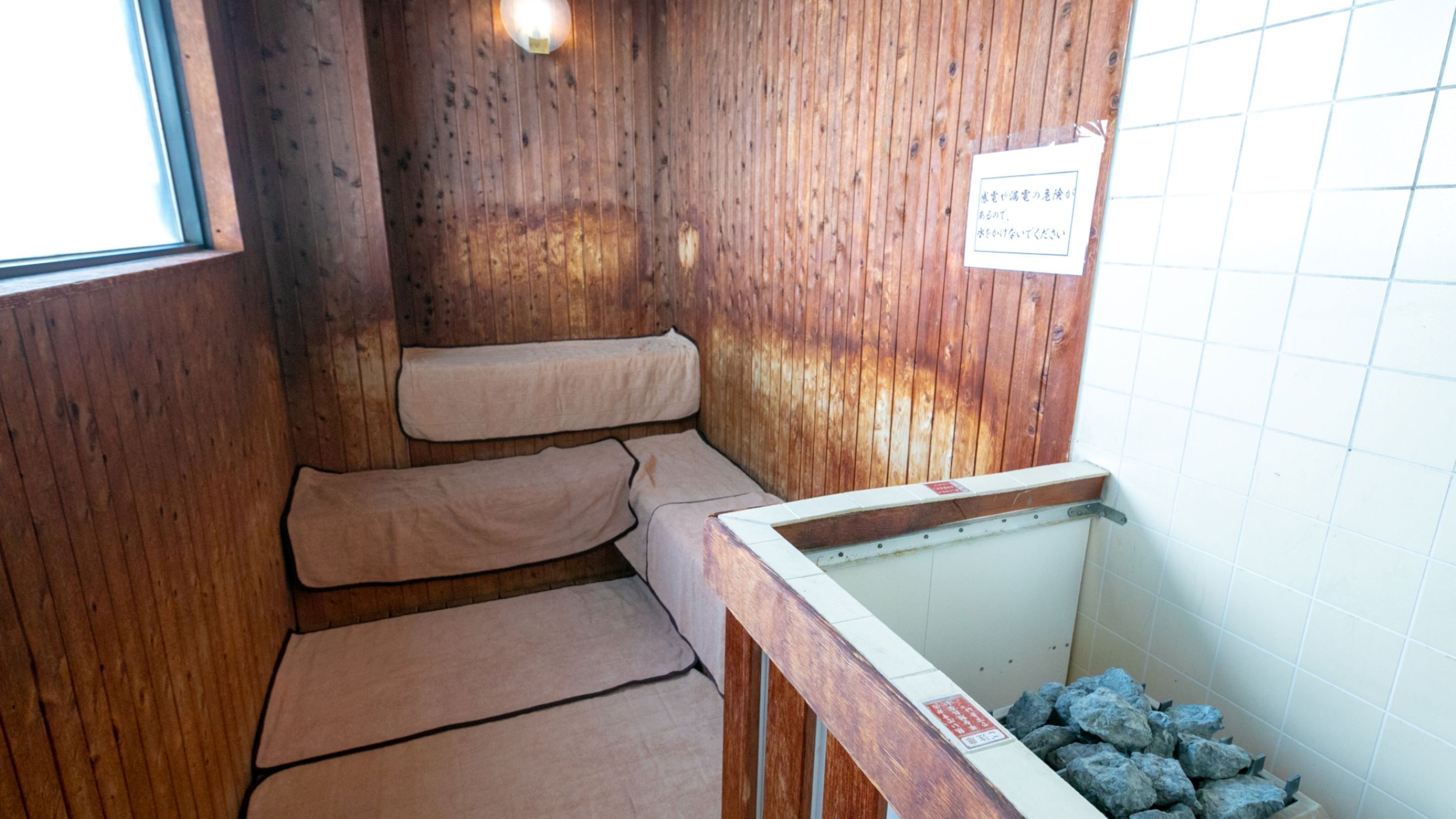 A wooden sauna room with benches and a tiled wall.