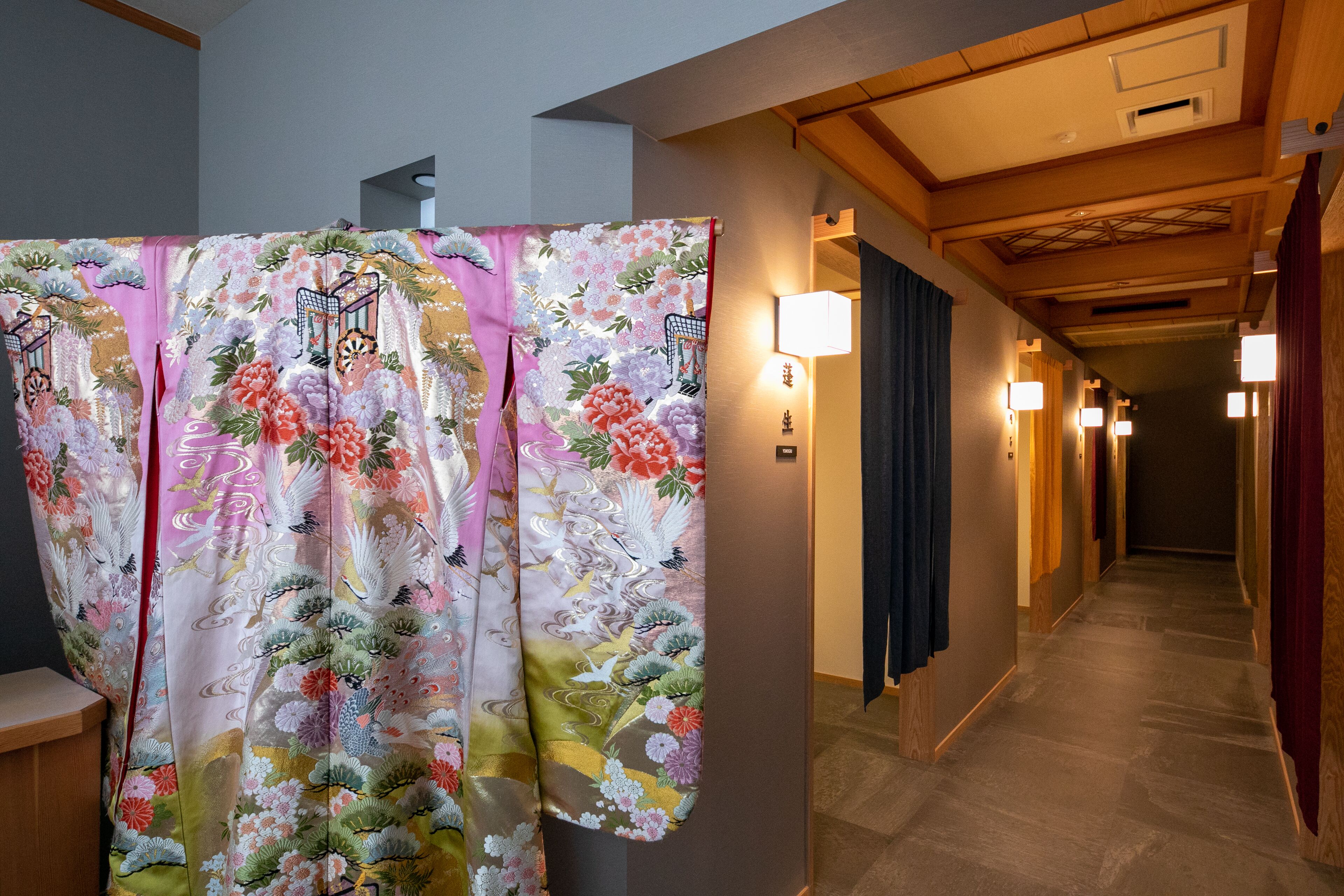 Un pasillo con decoración japonesa tradicional, que incluye una colorida pantalla shoji y paneles de madera.