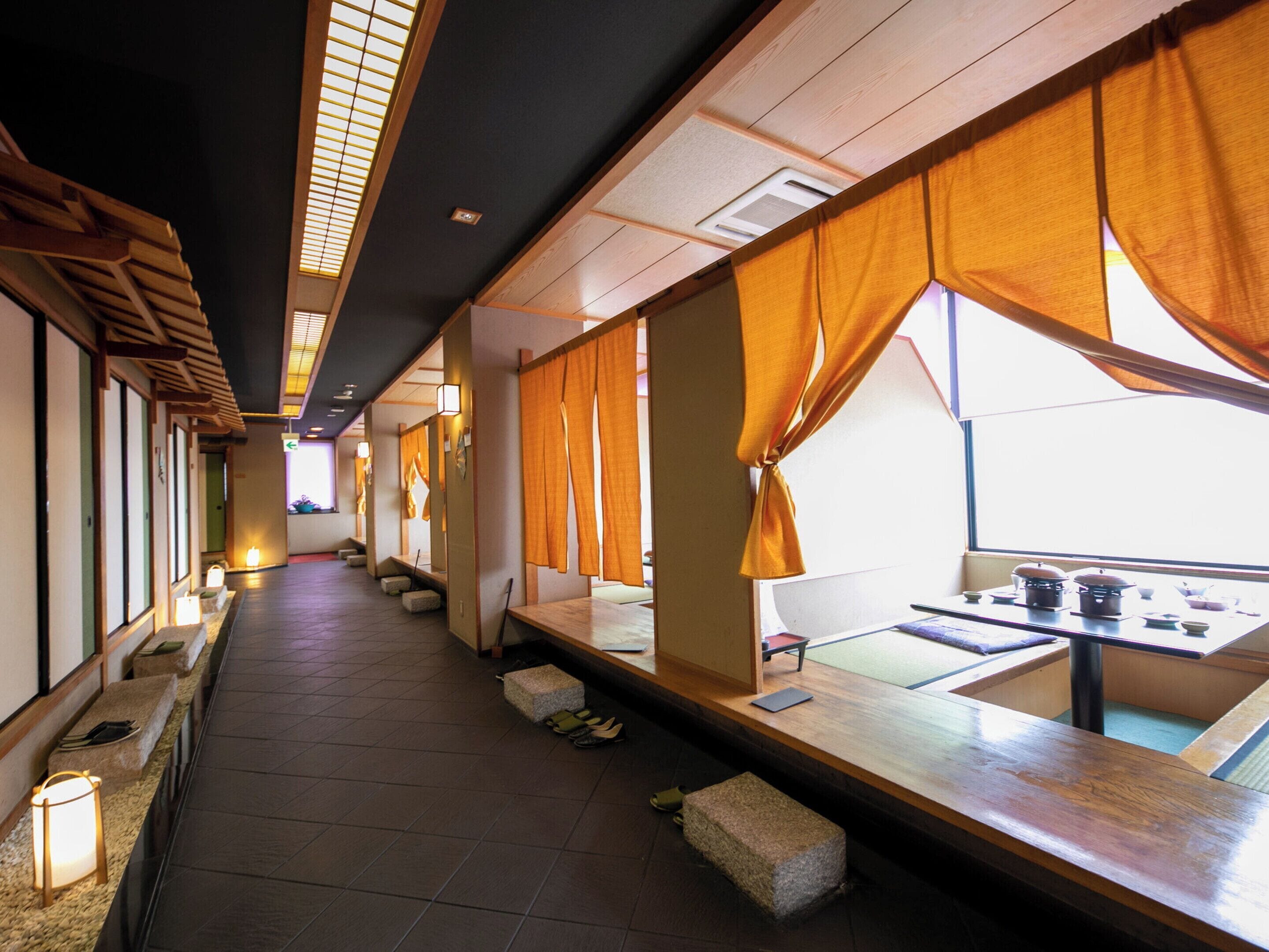 A traditional Japanese-style restaurant with tatami mat flooring, low tables, and sliding doors.