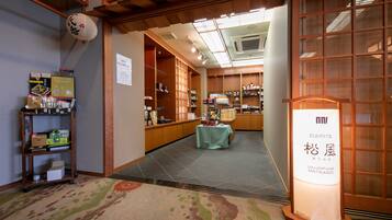 A traditional Japanese interior with a reception desk, shelves with merchandise, and a sign for a souvenir shop.