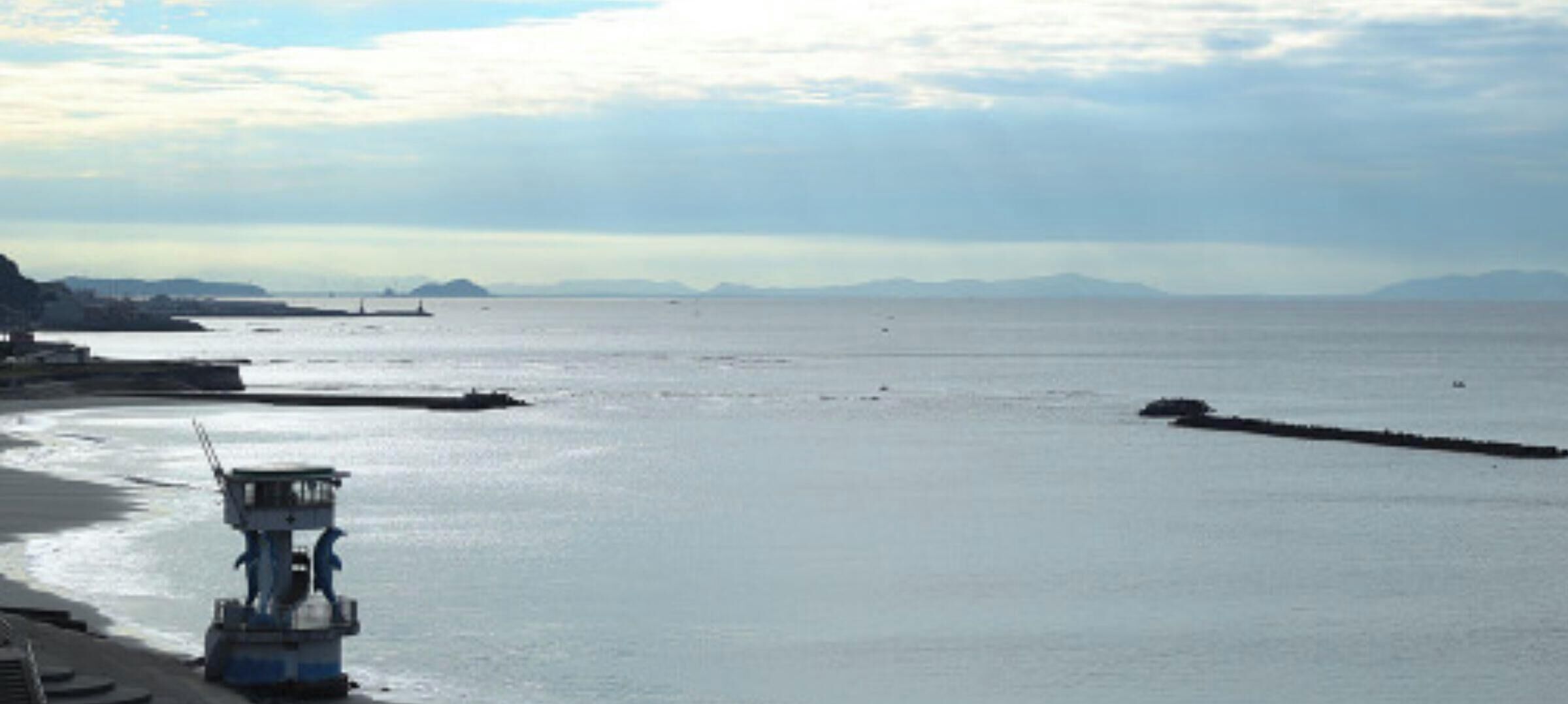 Eine Küstenlandschaft mit einem Rettungsturm, ruhigem Wasser und Bergen in der Ferne.