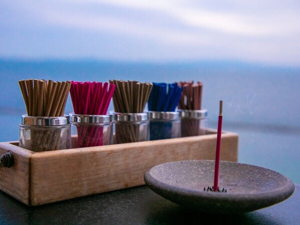 A wooden tray with incense sticks in various colors and a single lit incense stick on a stone plate. - Genjiko (Minamichita)