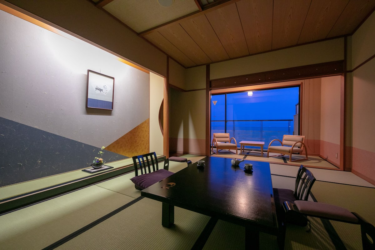 A traditional Japanese-style room with tatami flooring, a low table, and seating arrangements.