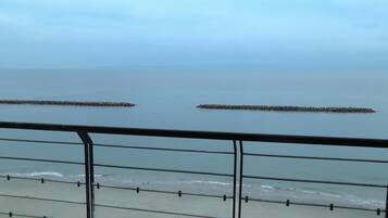 Vista de una playa con una baranda metálica al frente.