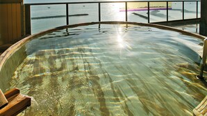 Un jacuzzi con terraza de madera y vista al mar y un muelle.