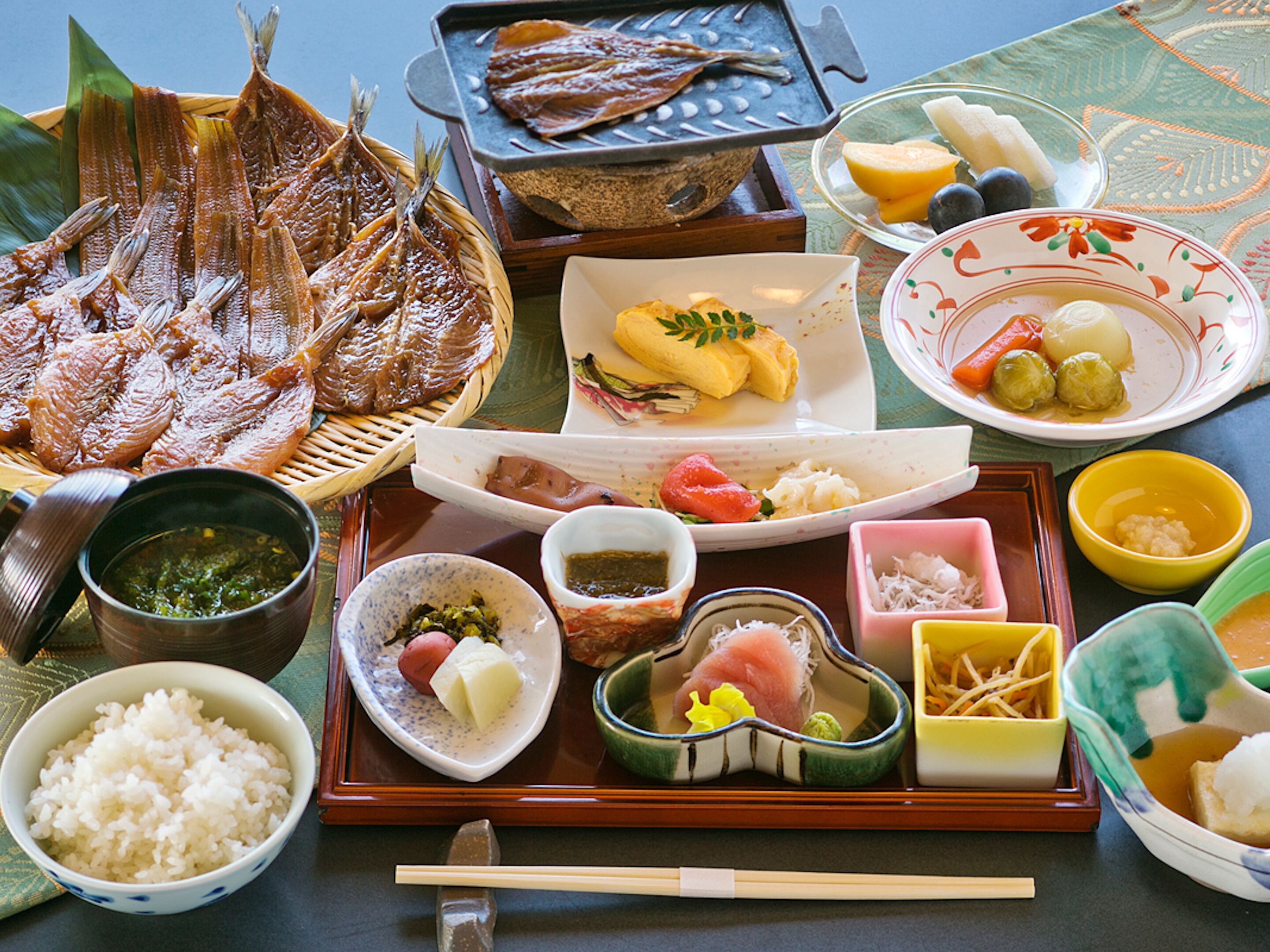 A variety of Japanese dishes including fish, rice, and vegetables on a tray.