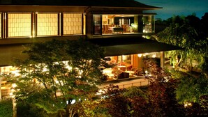 A two-story building with a dining area on the upper floor and a lounge area on the lower floor, surrounded by trees. - Seizan Yamato (Ito)