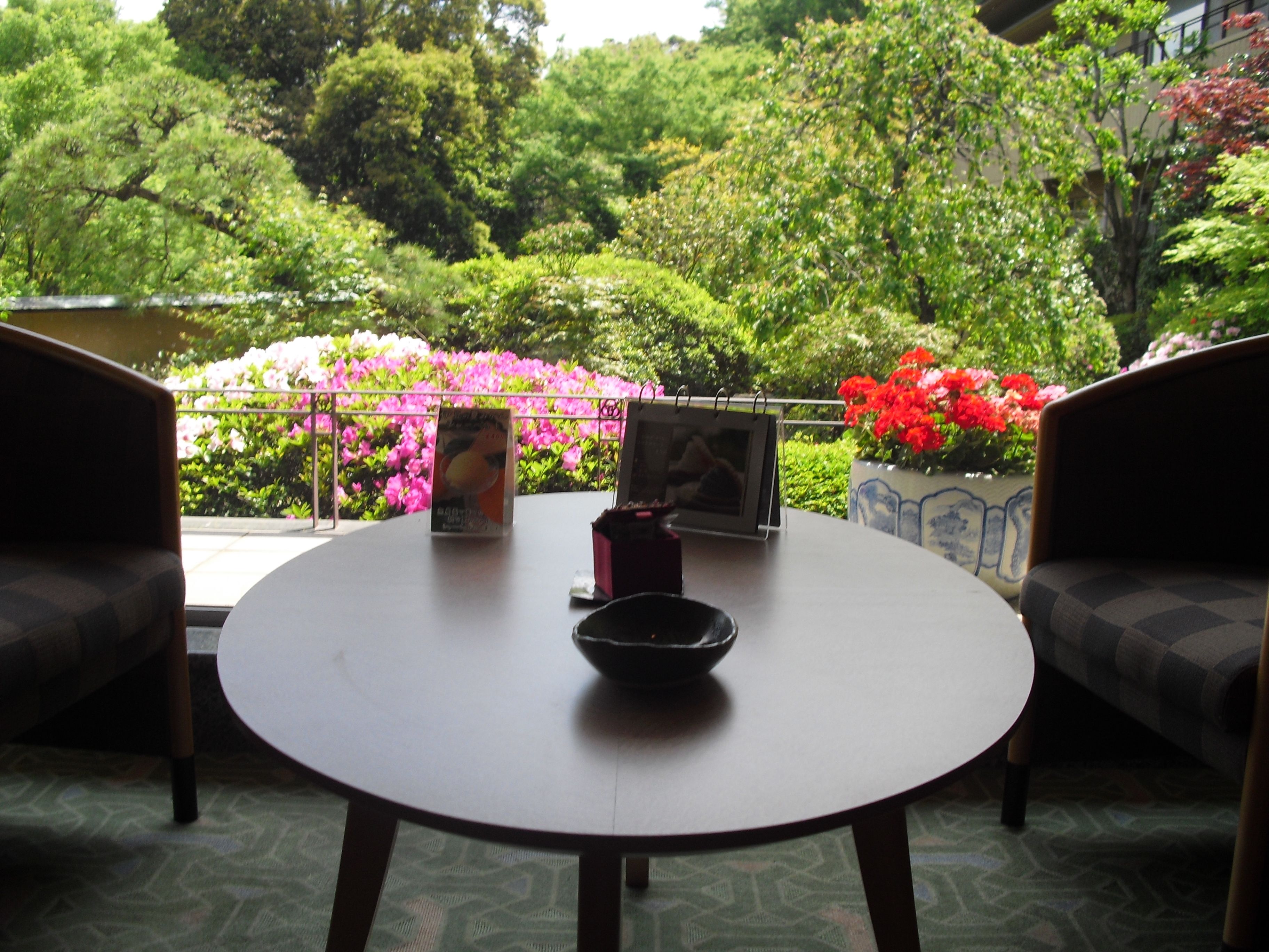A round table with a black bowl in the center, surrounded by two armchairs. A small potted plant is on the table.