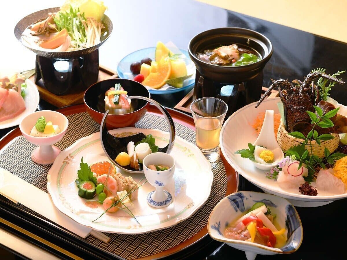 Une variété de plats, notamment des sashimis, des légumes et une sorte de fondue, présentés sur un plateau.
