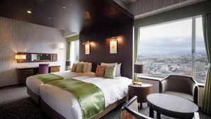 Habitación de hotel con una cama grande, un escritorio, una silla y vistas a la ciudad.