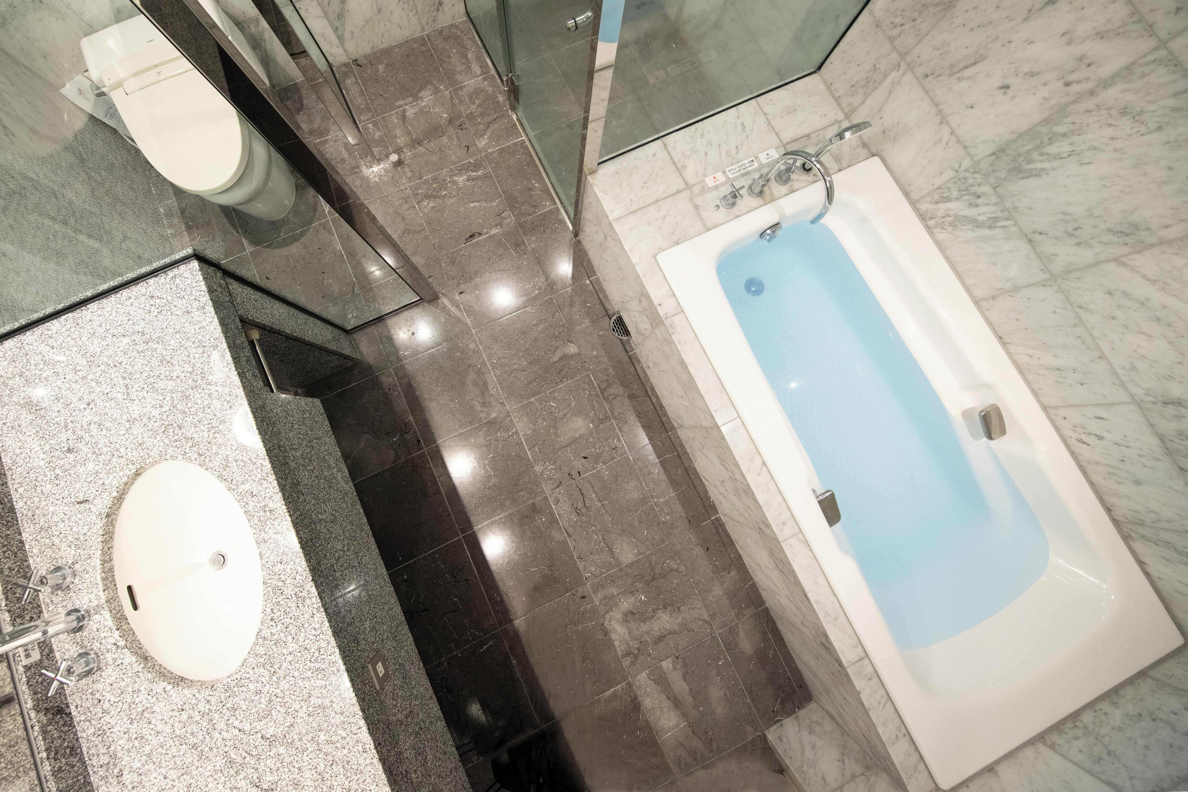 A bathroom with a marble floor, a white sink, a bathtub, and a toilet.