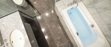 A bathroom with a marble floor, a white sink, a bathtub, and a toilet.
