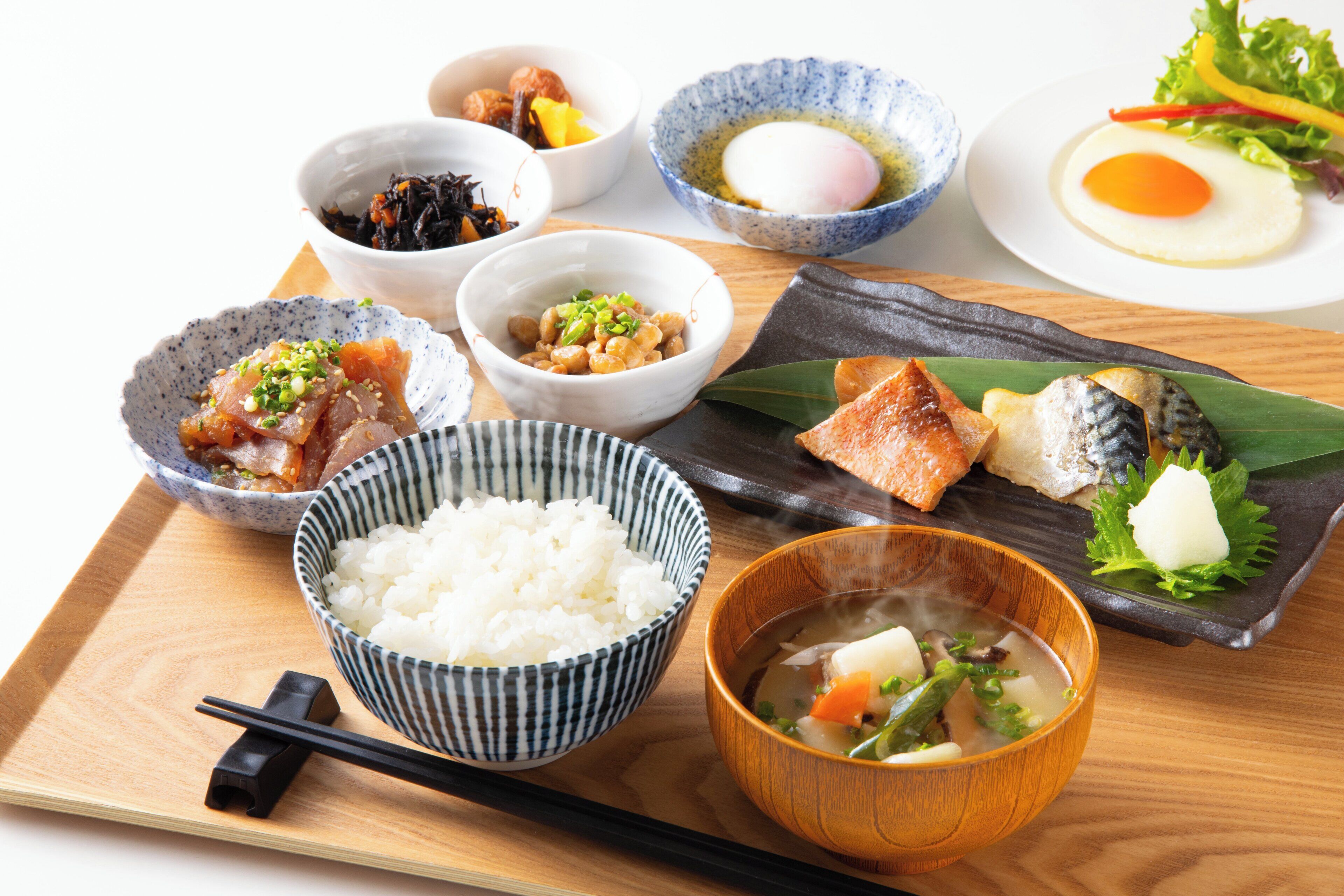 A wooden tray with various Japanese dishes including rice, soup, and sashimi.
