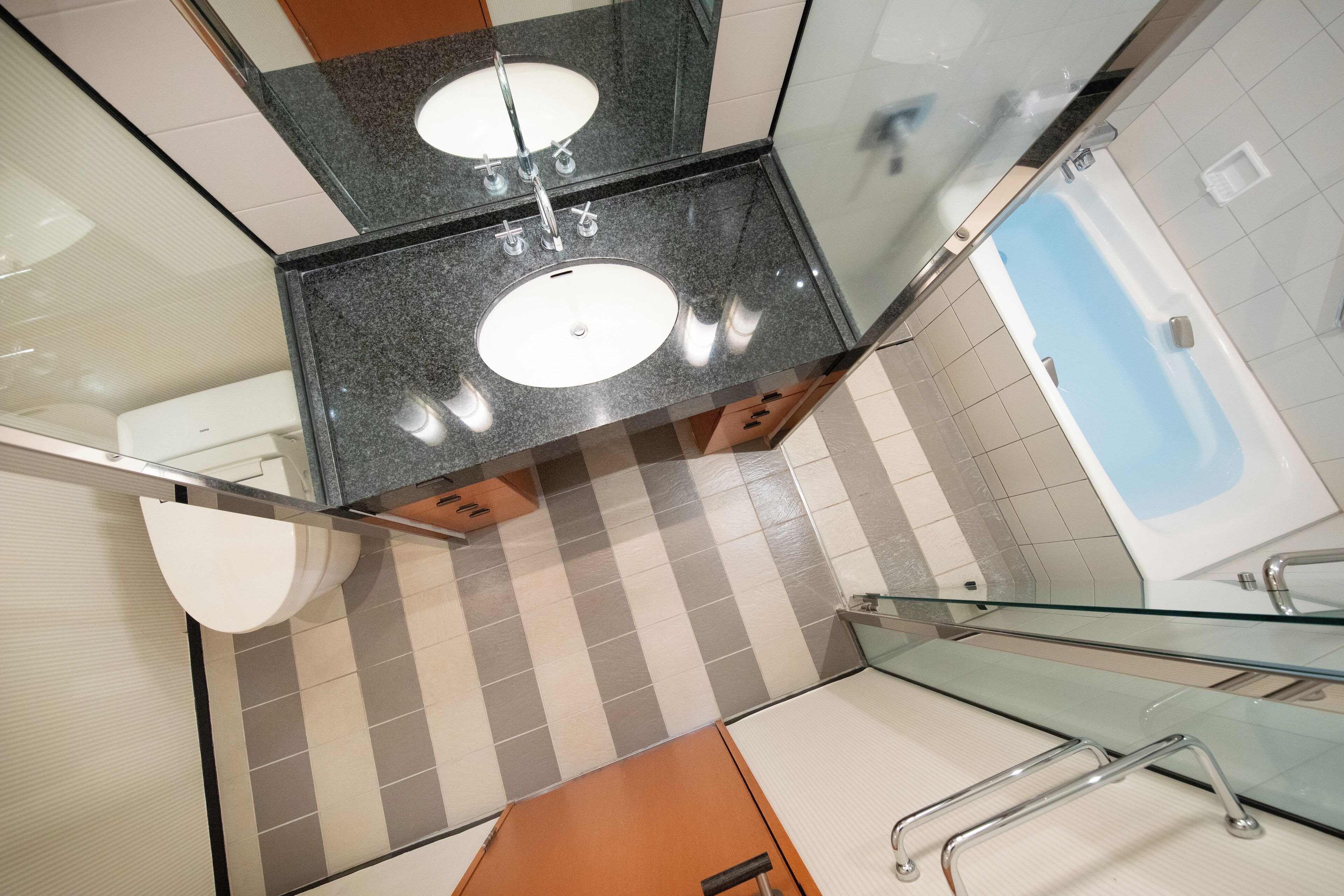 A modern bathroom with two sinks, a glass shower enclosure, and a checkered floor pattern.