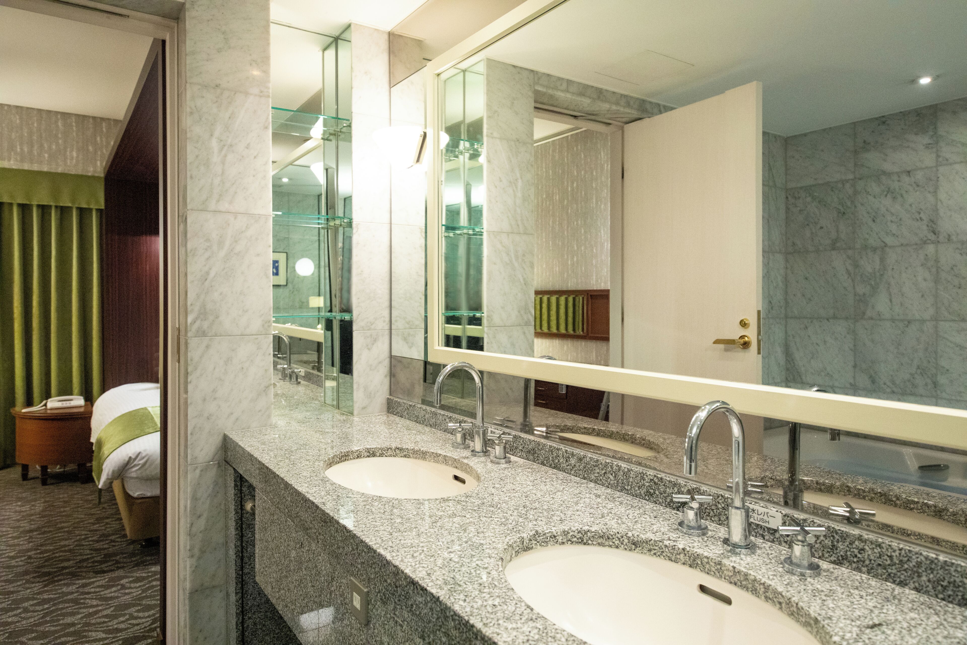 A hotel bathroom with two sinks, a large mirror, and a shower area.