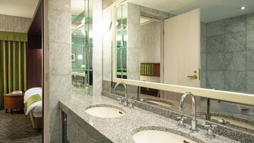 A hotel bathroom with two sinks, a large mirror, and a shower area.