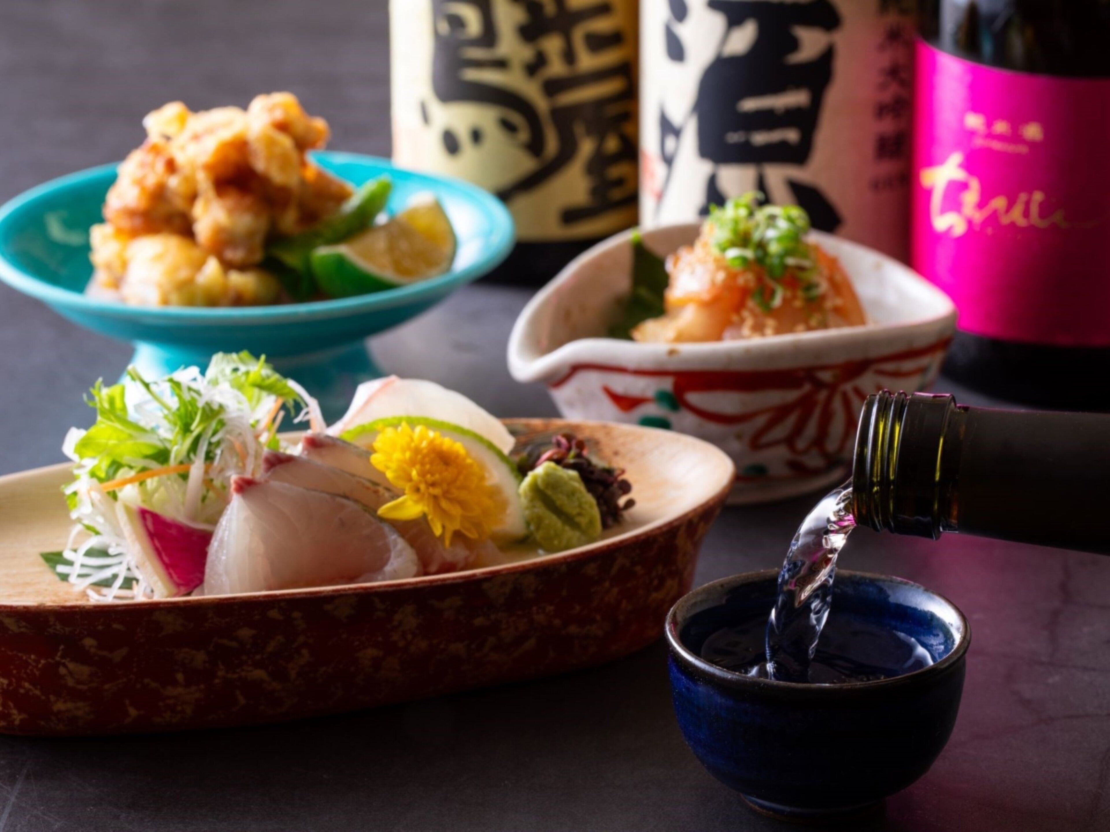 A table with various dishes, a bottle of drink, and a small bowl.
