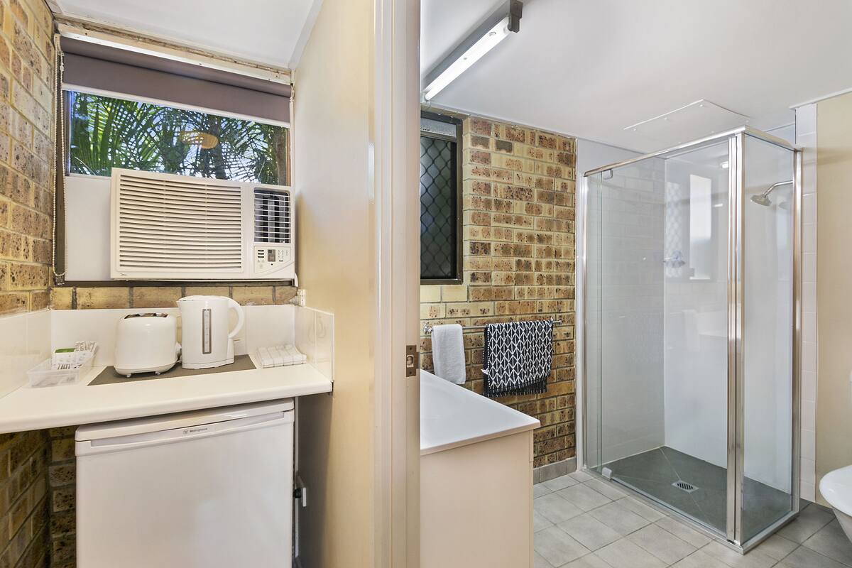 A modern bathroom with a shower, a coffee station, and a view of the outdoors.