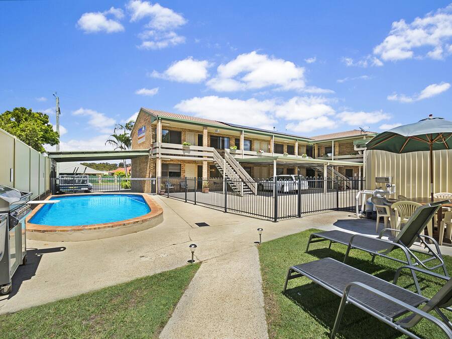 Un hotel con piscina, mobiliario exterior y un patio cubierto.