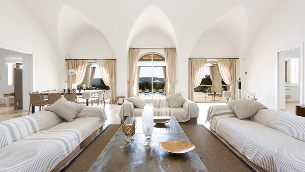 A spacious living room with a large table, two sofas, and a dining area with chairs. - Casa Murredda (Ostuni)