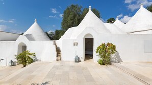 A building with multiple conical roofs and a central entrance. - Casa Murredda (Ostuni)